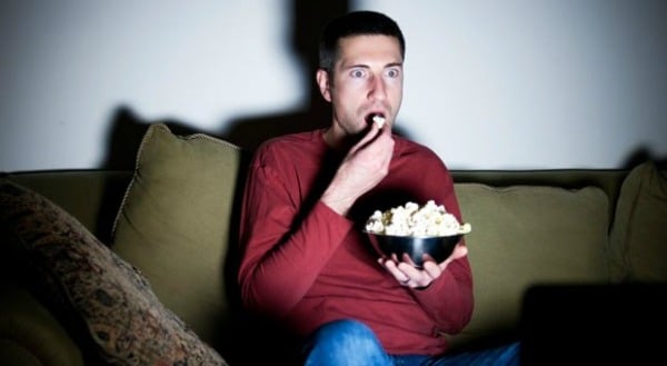 Man eating popcorn in front of TV