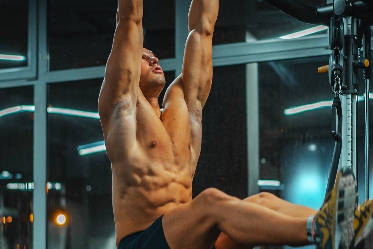 Image of a man hanging on a pull up bar. Source: Unsplash - 10 Best core workouts for men.