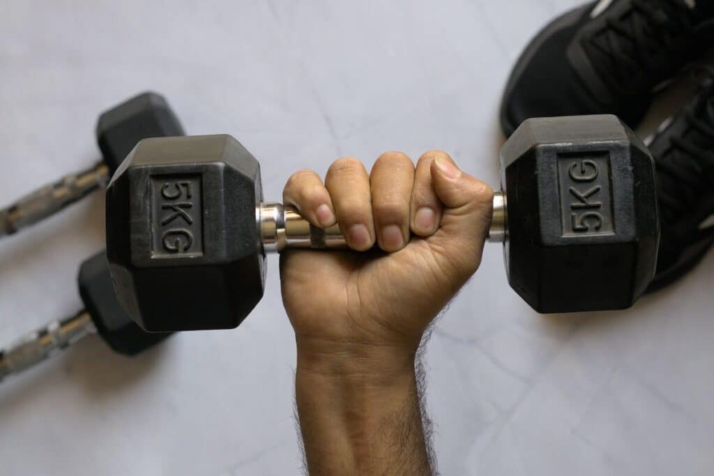 Image of a man's hand gripping a dumbbell. Source: Unsplash