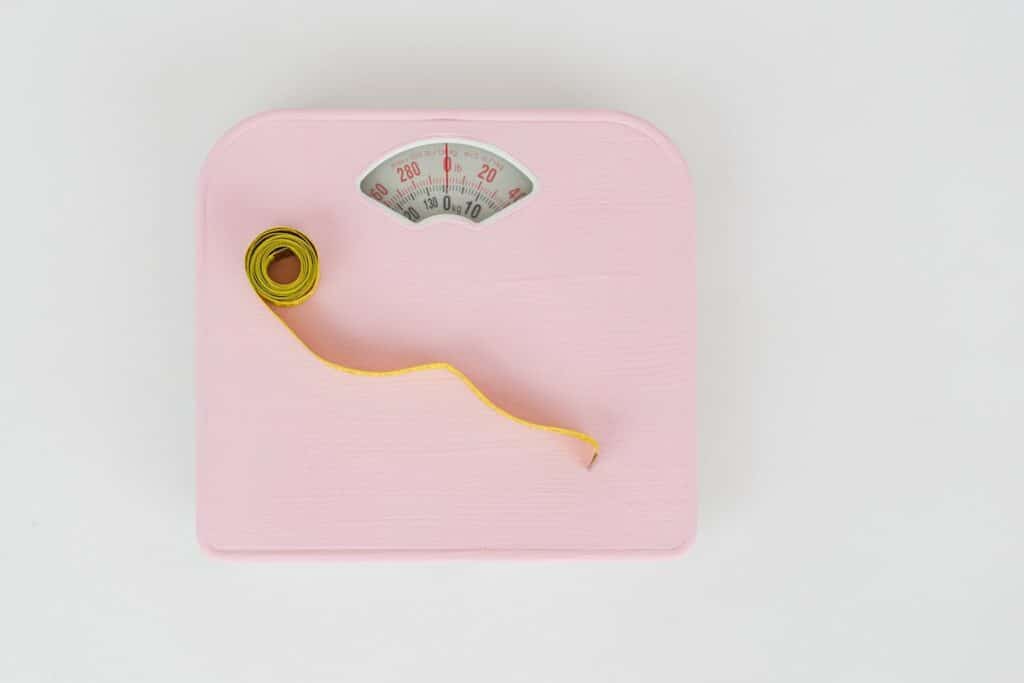 Image of a pink weighing scale and a measuring tape. Photo source: Pexels