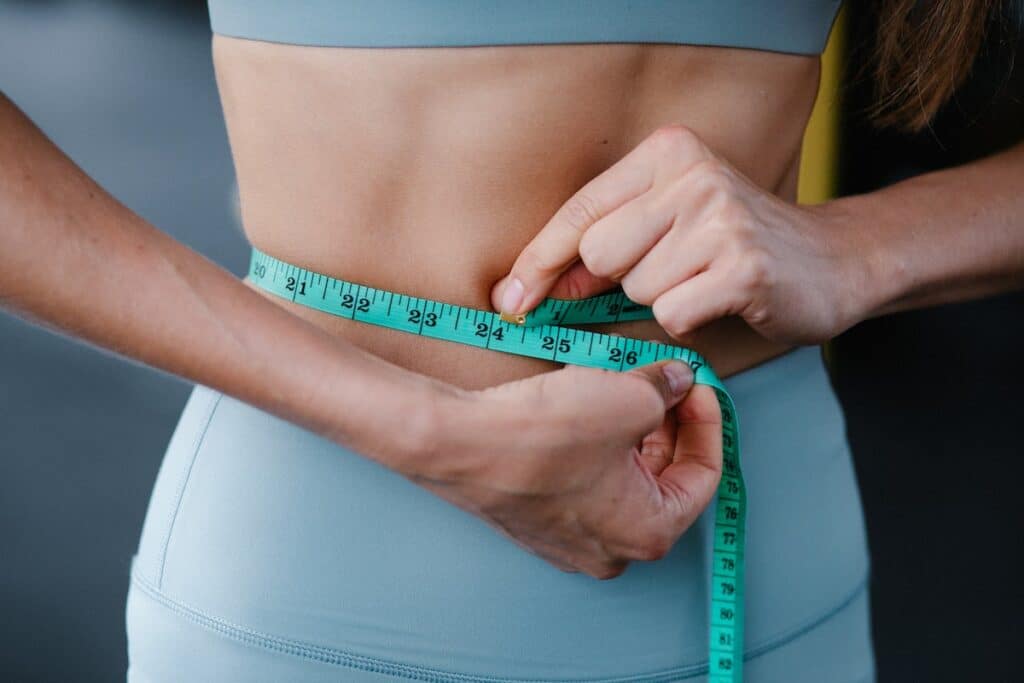 Image of a woman measuring her waist. Photo source: Pexels