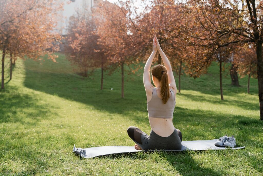 Image of a woman stretching on a yoga mat outdoors. Source: Pexels - Best morning stretch routines. 