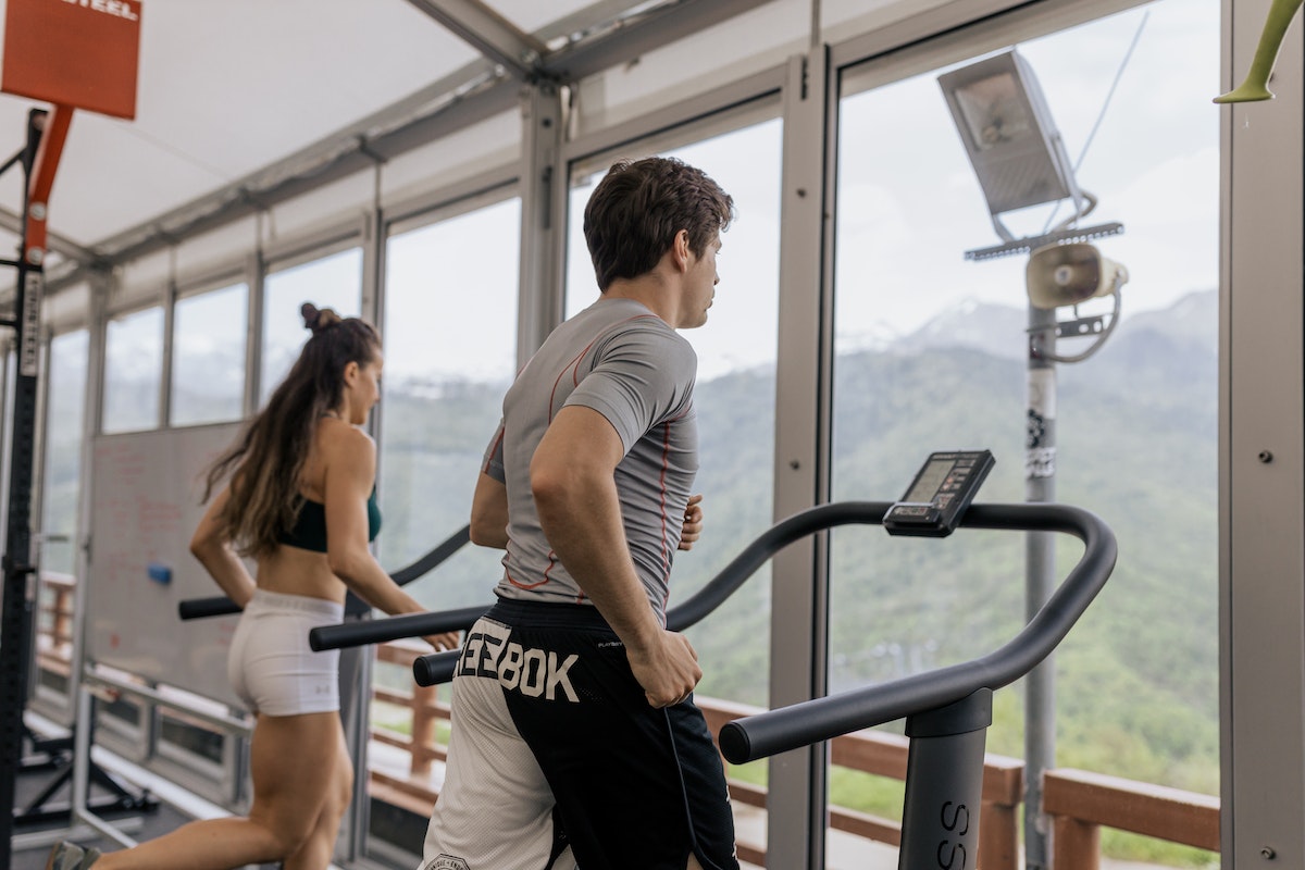 Image of a man and woman working out on a treadmill. Does walking on an incline burn belly fat?