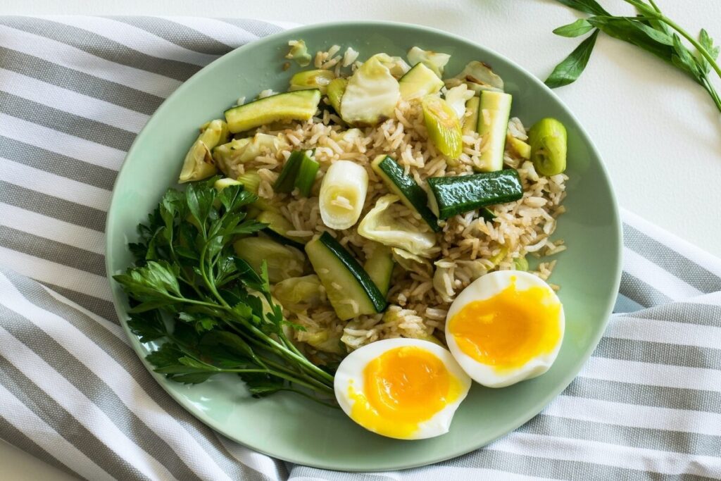 Image of a rice meal with zucchini soft boiled egg and parsley in a plate. Source: Pexels