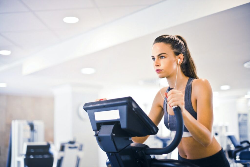 Image of a woman training on a treadmill inside a gym. Image source: Pexels