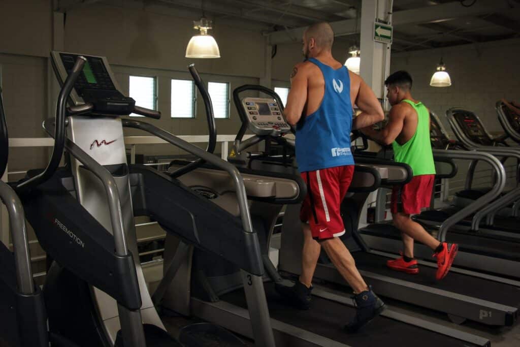 Image of two men running on treadmills. Source: Pexels