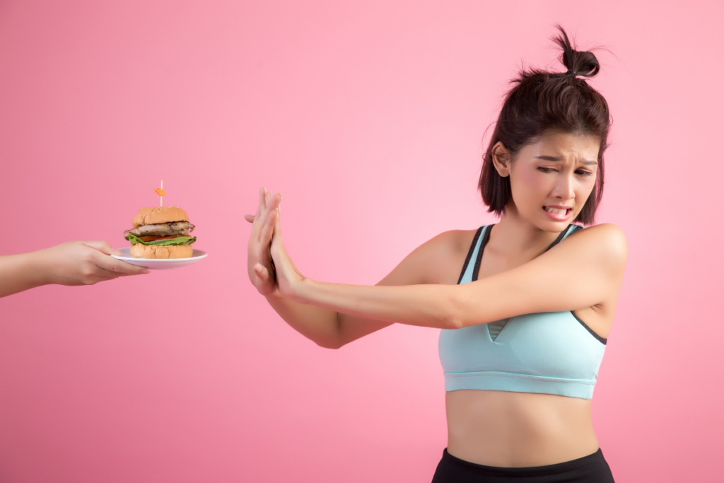 Asian women refuse fast food because of slimming on pink. Image source: freepik