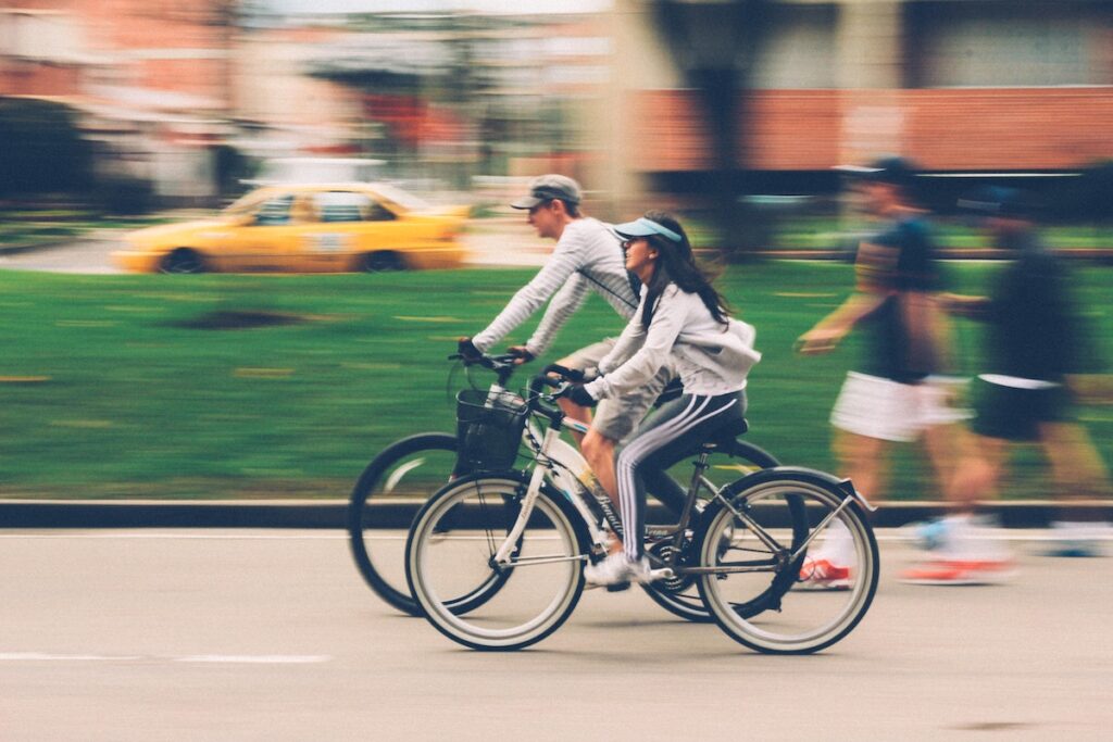 Image of two bikers and people walking in a park. Source: Pexels
