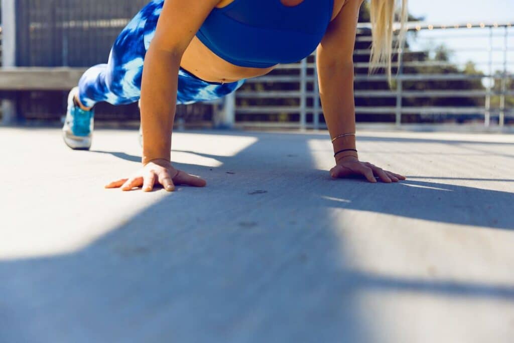 Image of a woman doing a plank on a concrete. Source: Unsplash