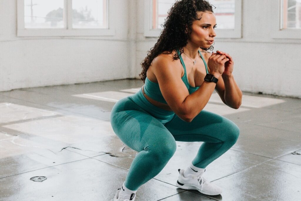 Image of a woman doing squats in a 30 minute HIIT workout. Source: Unsplash