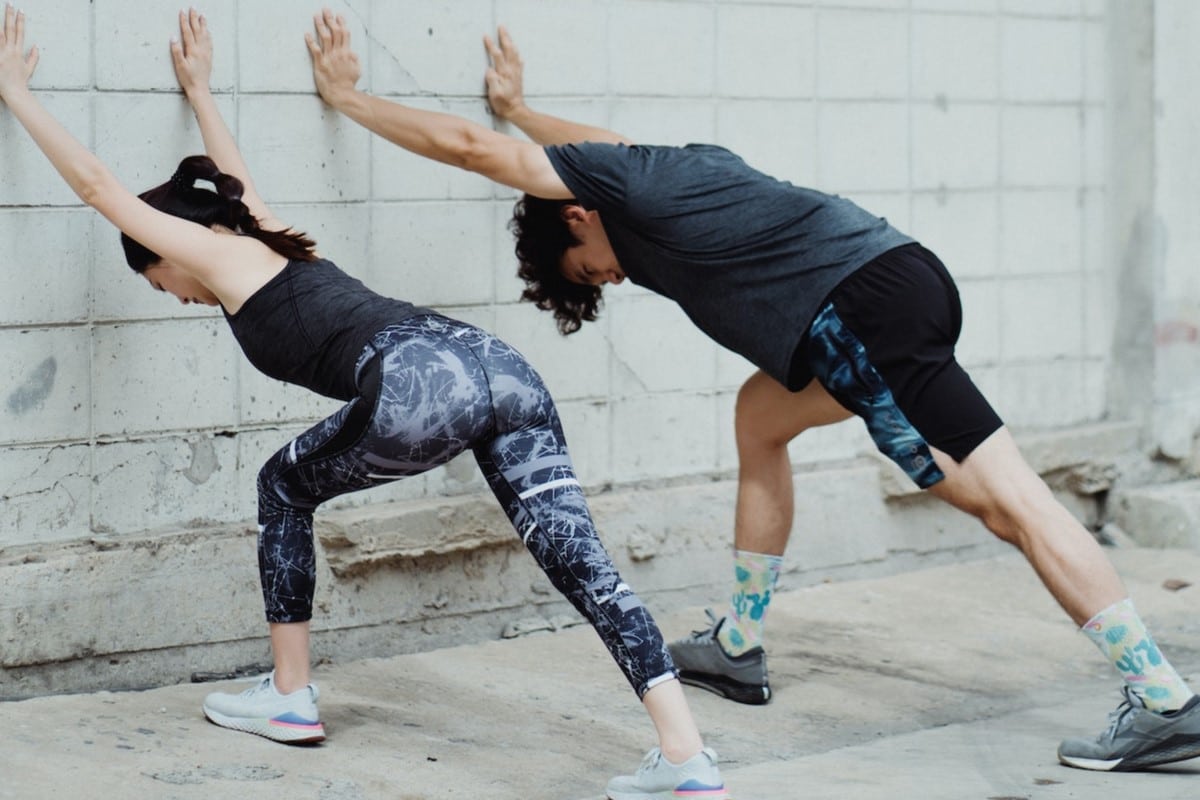 Image of two people doing a soleus stretch on a wall