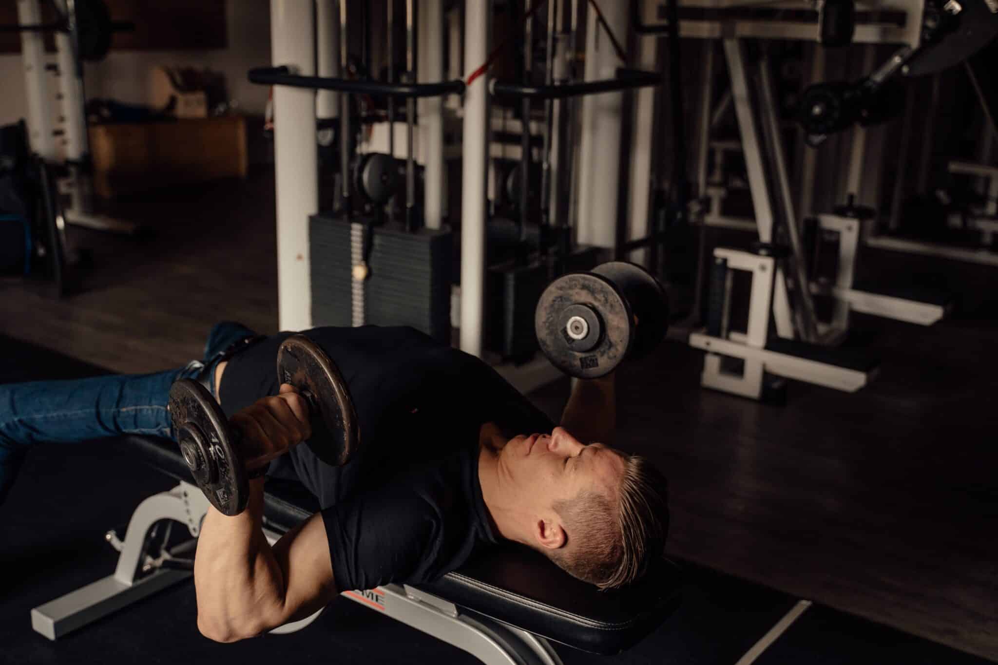 Image of a man doing a chest workout with dumbbells. Source: unsplash
