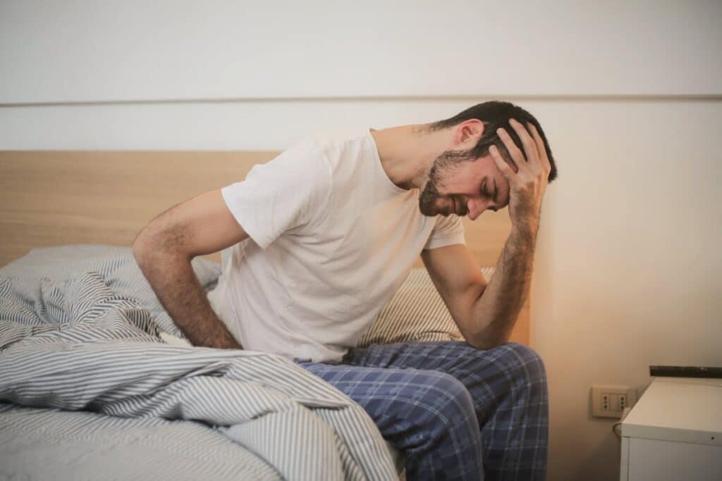 Image of a man feeling nauseous and holding his stomach. Source: Pexels