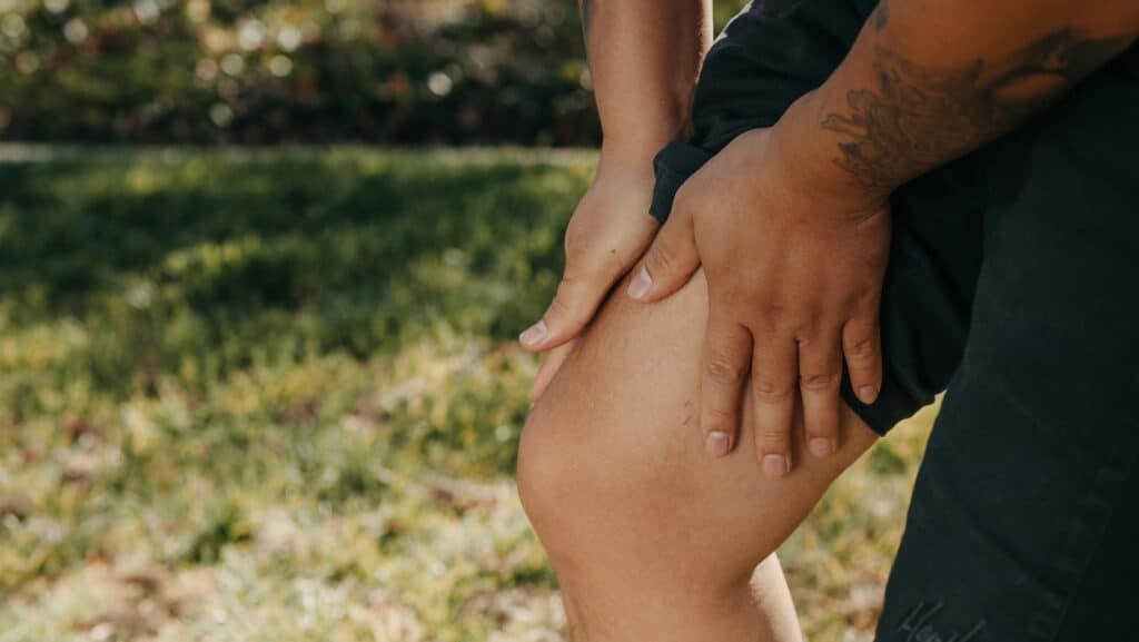 Image of a man holding his leg. Source: Pexels