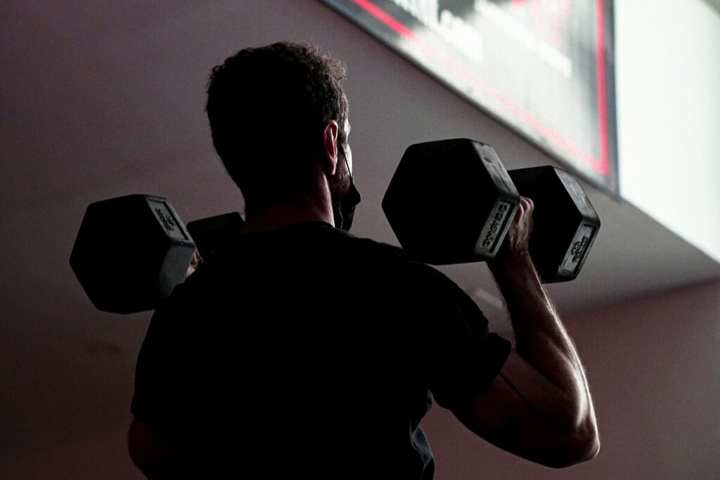 Image of a man lifting a pair of dumbbells. Source: unsplash